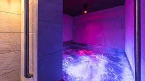 Un bain à remous avec un mur en pierre et un luminaire rouge.