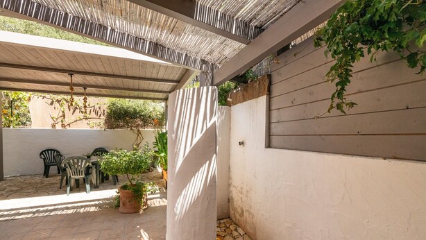 Un patio abrité avec un sol en pierre, un mur blanc et un plafond en bois.
