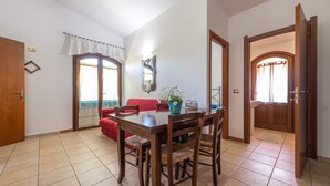 Un coin repas avec une table et des chaises en bois, un canapé rouge et une fenêtre avec des rideaux.