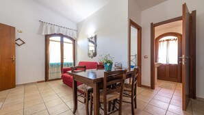 Un comedor con una mesa y sillas de madera, un sofá rojo y una ventana con cortinas.