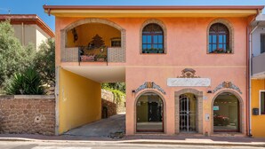 Un edificio de dos pisos con fachada amarilla, ventanas arqueadas y un balcón.