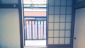 A room with a sliding door leading to an outdoor area with a wooden fence and a clothes drying rack. - Hikawacho Guest House (Soka)