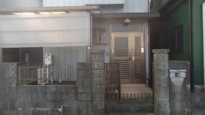 A gated entrance with a metal gate, a wooden door, and a small set of steps leading to a door with a keypad lock. - Hikawacho Guest House (Soka)