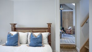 A bedroom with a wooden headboard, white bedding, and two blue pillows. - Birdcage Cottage- Woodburner & Free Wi-Fi (Kingsand)