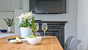 A dining table with a white bowl of grapes, a white pitcher, and a bottle of white wine. - Birdcage Cottage- Woodburner & Free Wi-Fi (Kingsand)