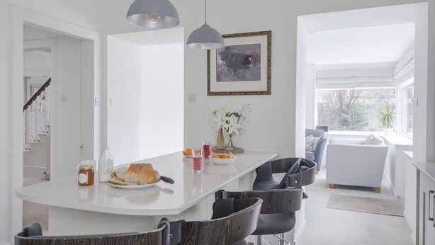 A modern kitchen with a white island, pendant lights, and a view to the living area. - Whitecraigs -  a rural that sleeps 8 guests  in 4 bedrooms (Elgin)