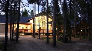 A cabin with a porch and a covered deck, surrounded by tall trees. - Moose Tracks Inn: Family Friendly and Wheelchair Accessible. (Island Park)