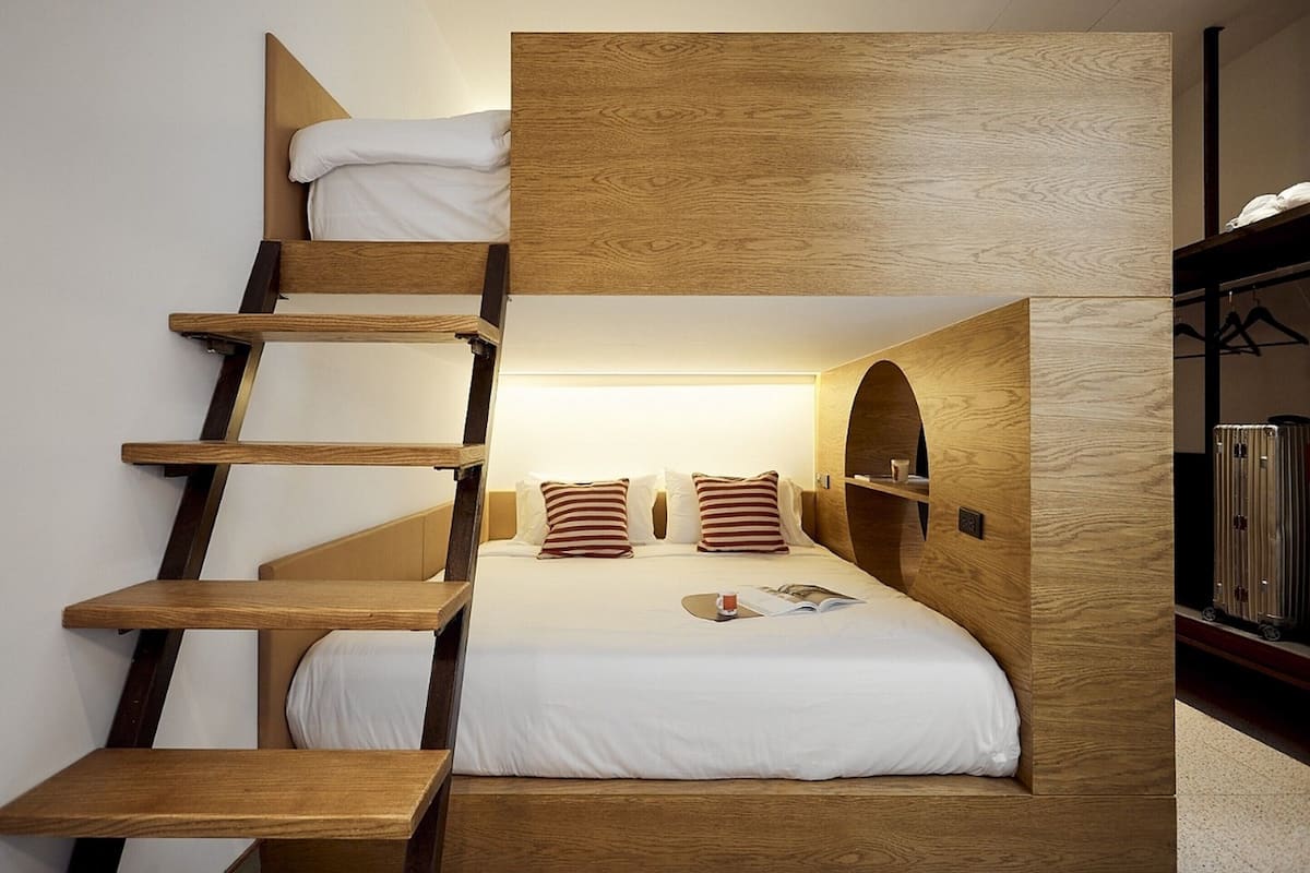 Un lit superposé en bois, avec une échelle et une lampe de lecture.