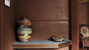 A room with a bench, a large woven basket, and a chair.
