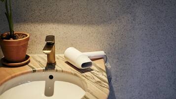 A bathroom sink with a marble countertop, a potted plant, and a handheld device on the counter.