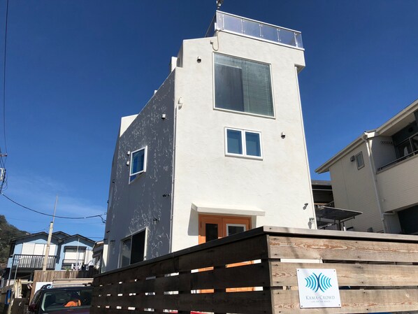 Un bâtiment moderne doté d’un toit plat, d’un balcon et d’une enseigne indiquant qu’il s’agit d’un club de plage.