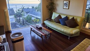 Uma sala de estar com sofá, mesa e vista para o mar.