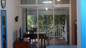 Een kamer met een grote schuifglazen deur die uitkomt op een balkon met uitzicht op groen en een trap.