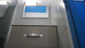 Een badkamer met een douchegedeelte betegeld in blauw, een witte wastafel en een spiegel.