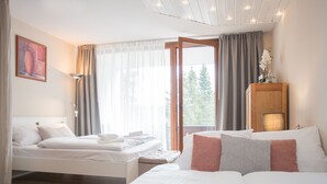 Een hotelkamer met een groot bed, een kleiner bed, een houten kast en een raam met gordijnen.