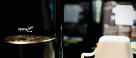 A coffee machine and a white cup on a table.