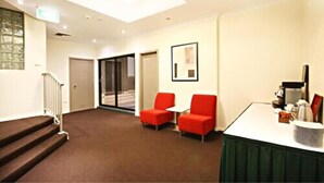 A hotel lobby with a staircase, red chairs, a reception desk, and a framed picture on the wall. - Central Studio Hotel Sydney (Haymarket)