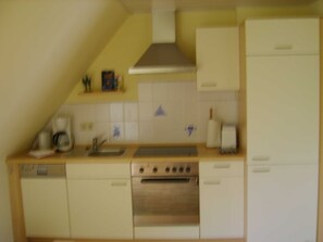 Una cocina con un fregadero, estufa y alacenas.