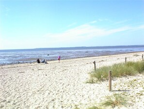 Una playa arenosa con algunas personas y una cerca de madera.