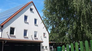 Ein zweistöckiges Gebäude mit rotem Ziegeldach, zahlreichen Fenstern und einer Garage.
