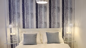 Un dormitorio con una cama, dos mesitas de noche y una pared con paneles de madera verticales.
