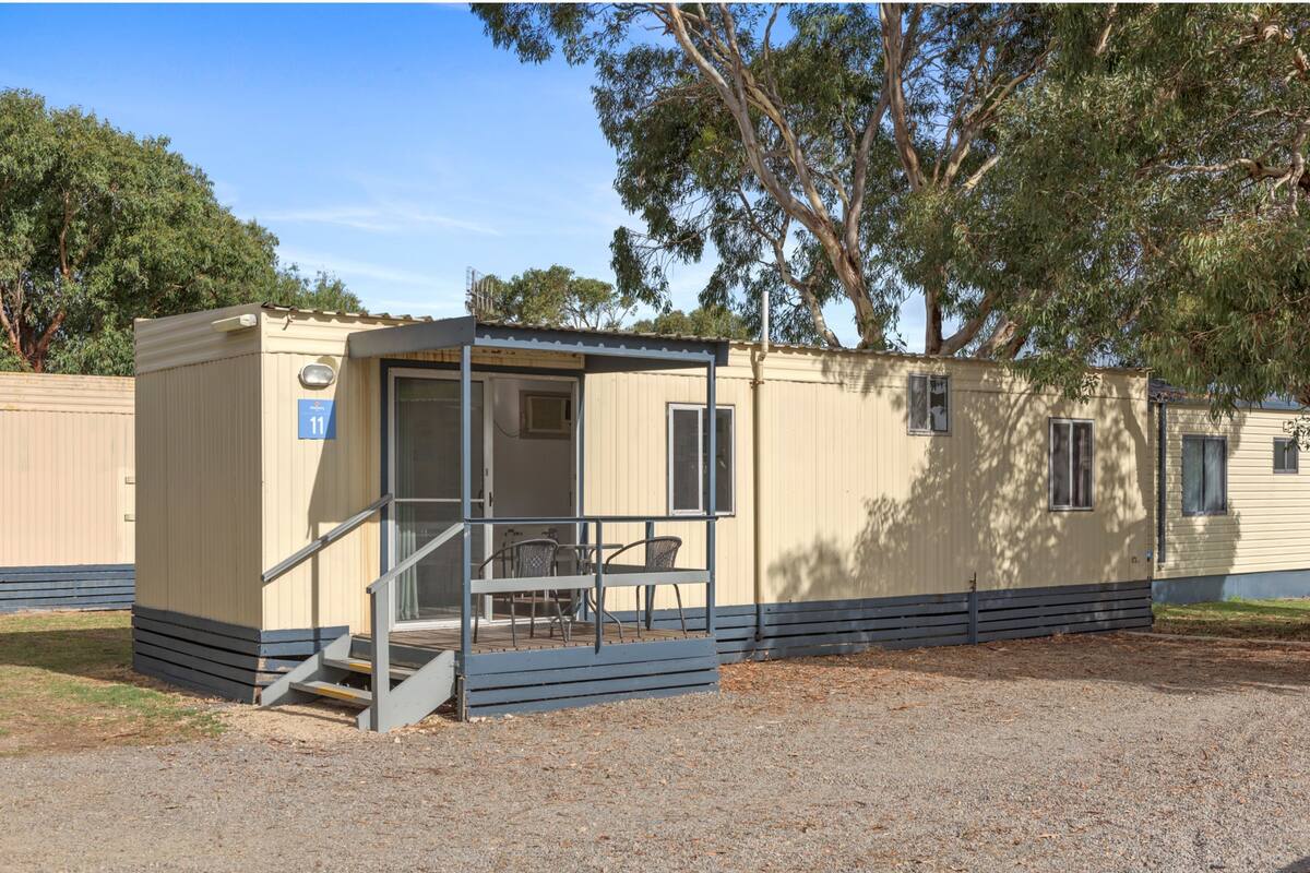 A single-story mobile home with a covered porch and a small outdoor seating area.