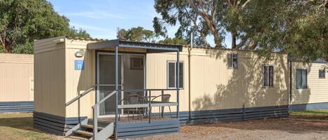 A single-story mobile home with a covered porch and a small outdoor seating area.