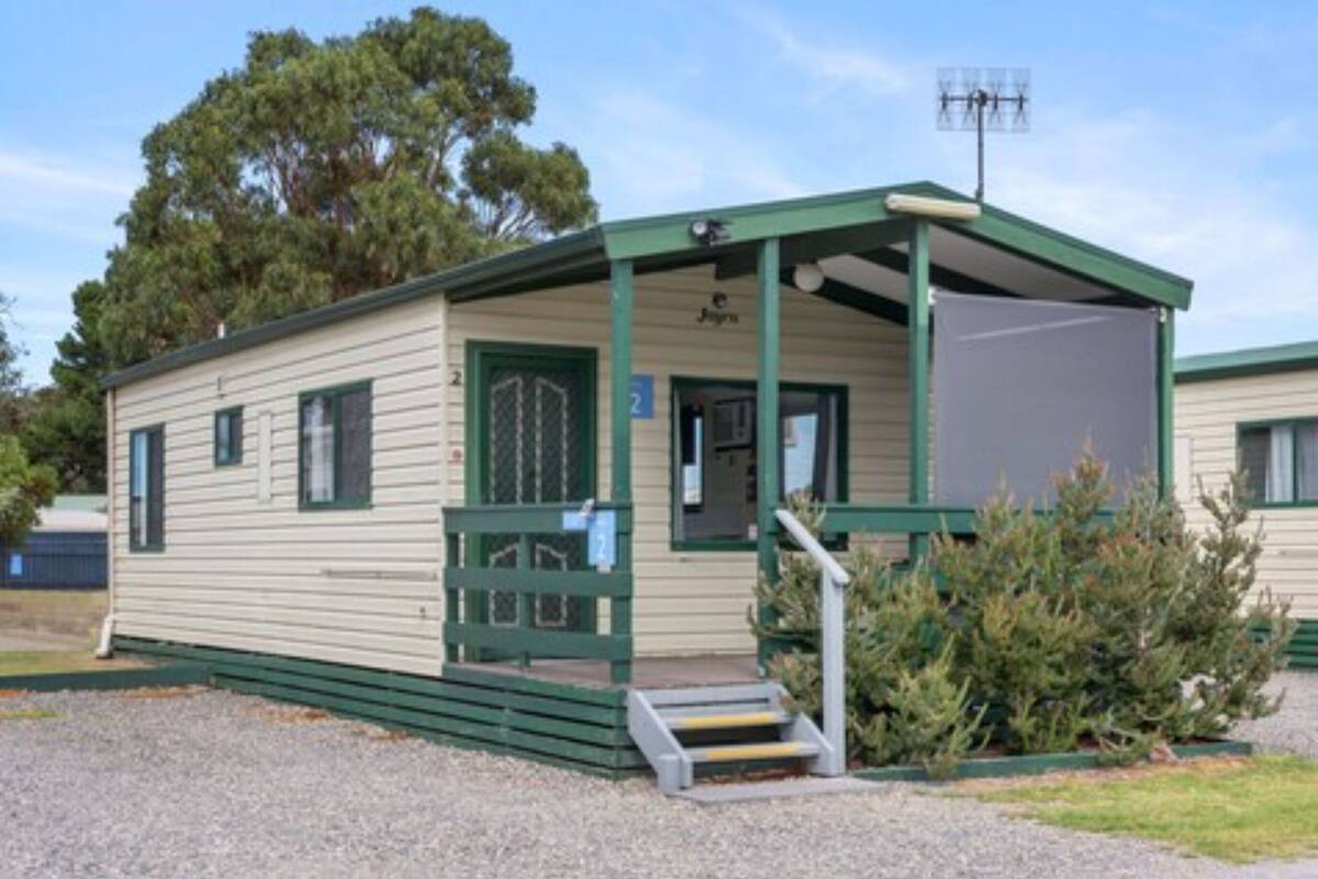 A single-story mobile home with a porch, a small set of steps leading to the entrance, and a sign indicating the number 2.