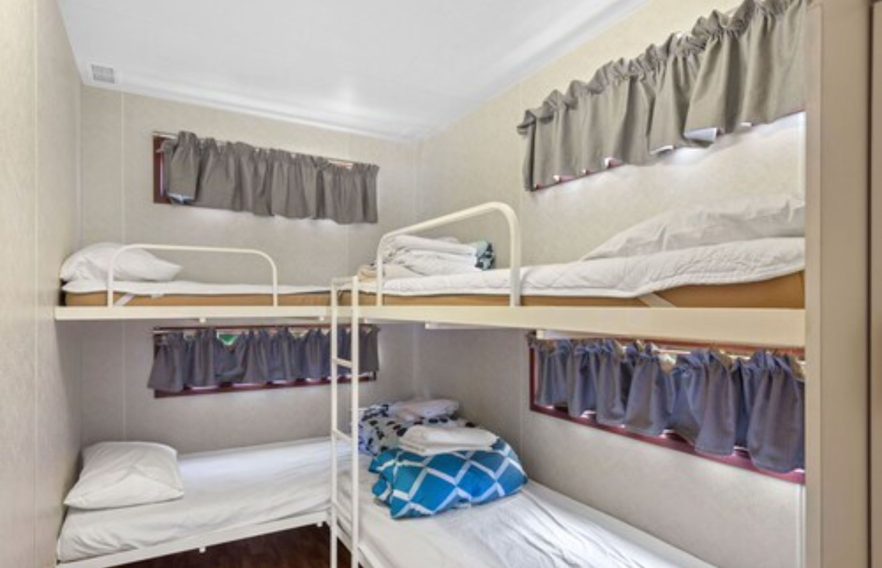 A bunk bed room with three levels, each with a mattress and pillows.