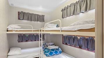 A bunk bed room with three levels, each with a mattress and pillows.