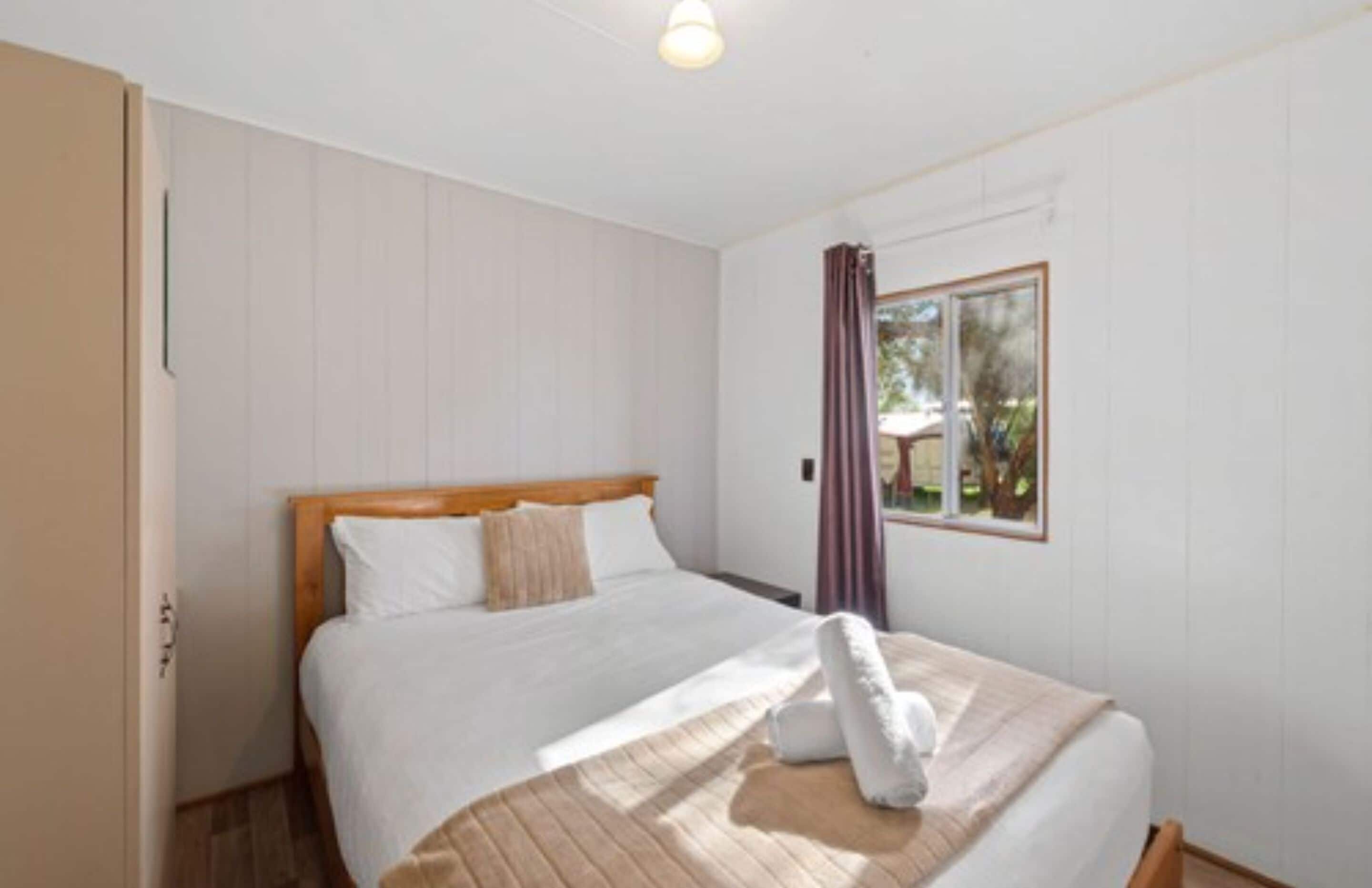 Een slaapkamer met een bed, een raam met gordijnen en een deur.