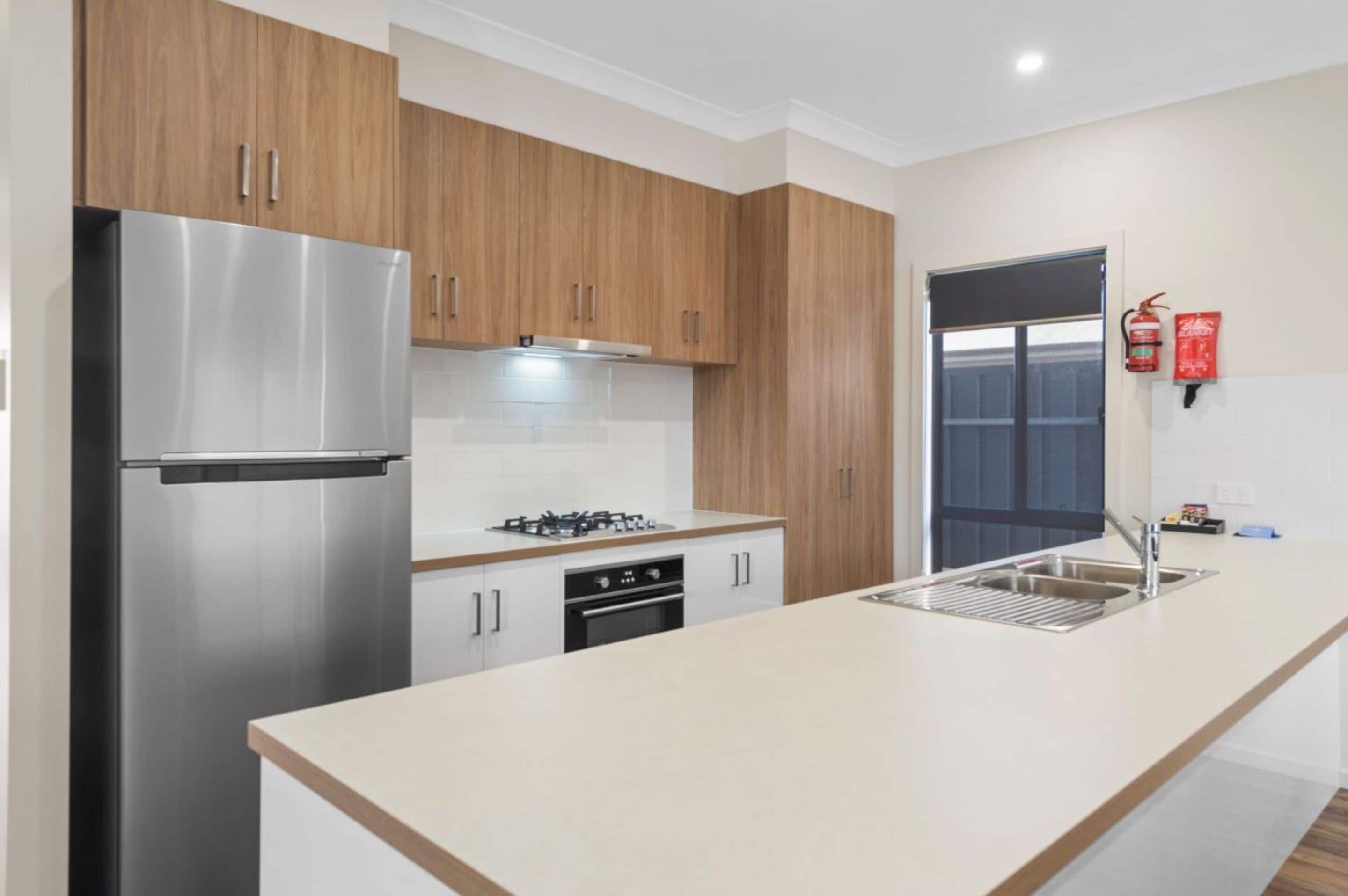 A modern kitchen with stainless steel appliances, wooden cabinets, and a large island with a sink.