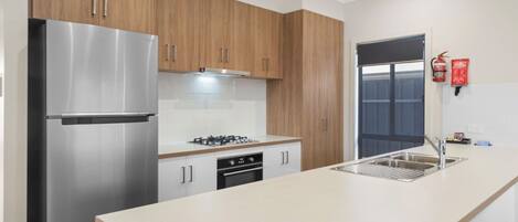 Una cucina moderna con elettrodomestici in acciaio inossidabile, mobili in legno e una grande isola con lavello.