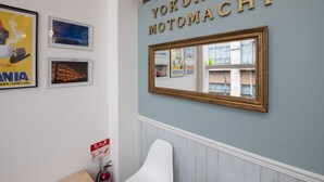 Una habitación con un espejo de pared, obras de arte enmarcadas y un letrero que dice "YOKOHAMA MOTOMACHI".
