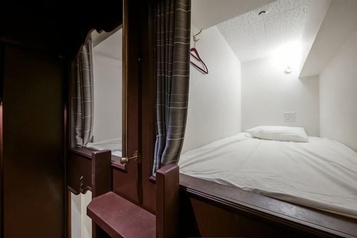 Un dormitorio con cama, mesita de noche, espejo y perchero.