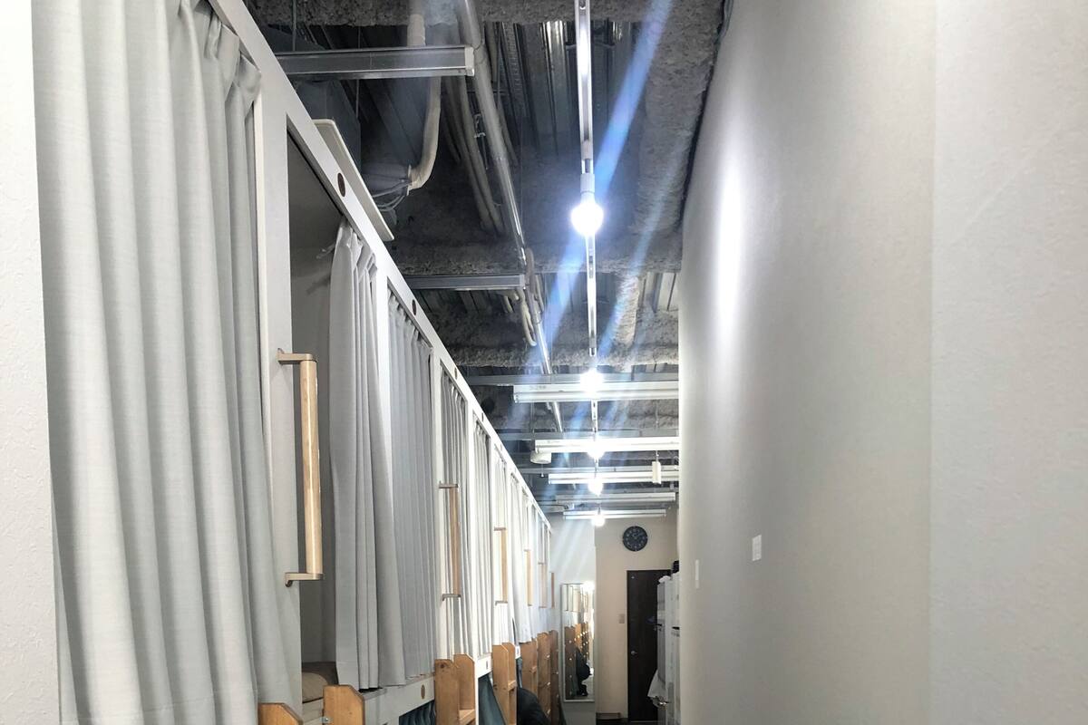A corridor with bunk beds, wooden shelves, and curtains.