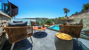 Une terrasse sur le toit, aménagée avec des meubles en osier, une table ronde et offrant une vue sur une piscine et un paysage lointain.