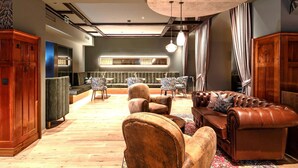 Eine großzügige Lobby mit Ledersofas, einer Bar und einer Sitzecke mit gemusterten Stühlen.