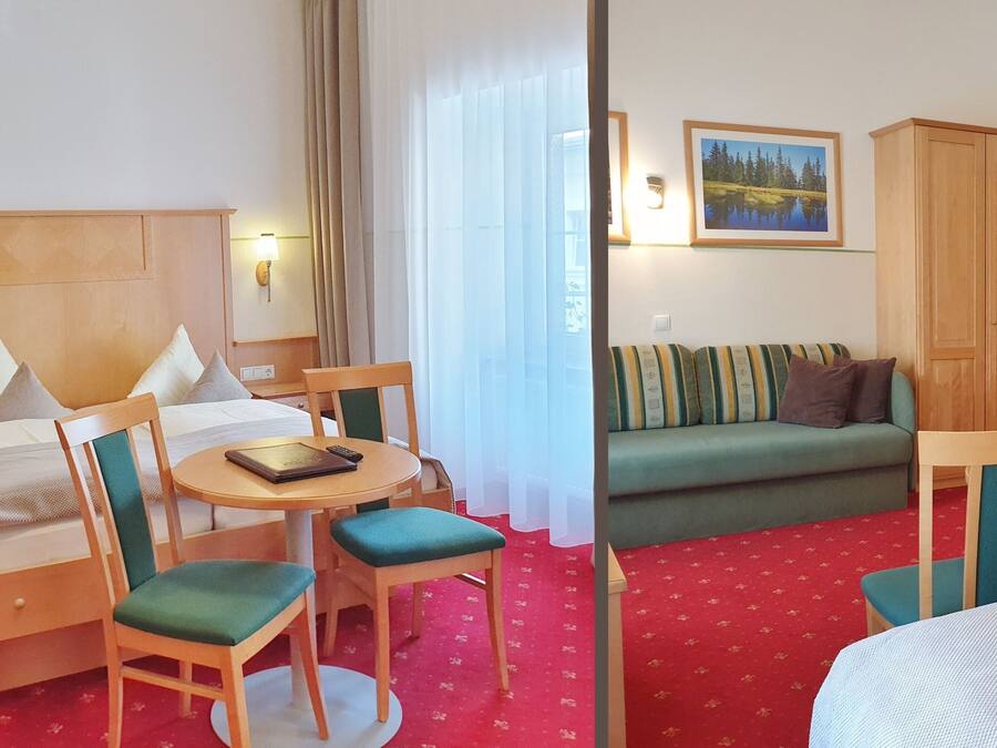 Una habitación de hotel con cama, una mesa redonda con sillas, un sofá y un armario.