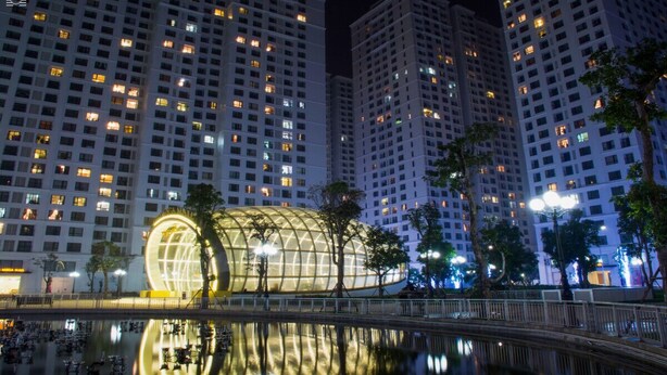 A nighttime view of a modern building complex with a distinctive glass structure in the center, surrounded by high-rise residential buildings. - Park Hill Times City Apartment						 						 (Hanoi)