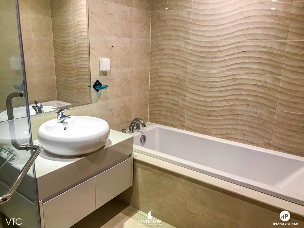 A modern bathroom with a large bathtub, a round sink, and a glass shower enclosure.