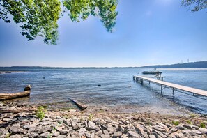 A rocky shoreline with a wooden dock extending into calm water.
