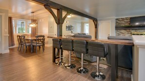 A modern kitchen with a wooden bar and four bar stools. - Waterfront Home w/ Hot Tub in Wrightsville! (Wrightsville)