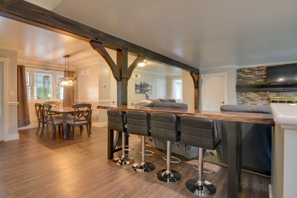 A modern kitchen with a wooden bar and four bar stools.