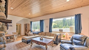 A cozy living room with a wooden ceiling, a sofa set, a leather armchair, a coffee table, and a bookshelf. - Secluded Camp Connell Home w/ Deck + Fireplace! (Camp Connell)