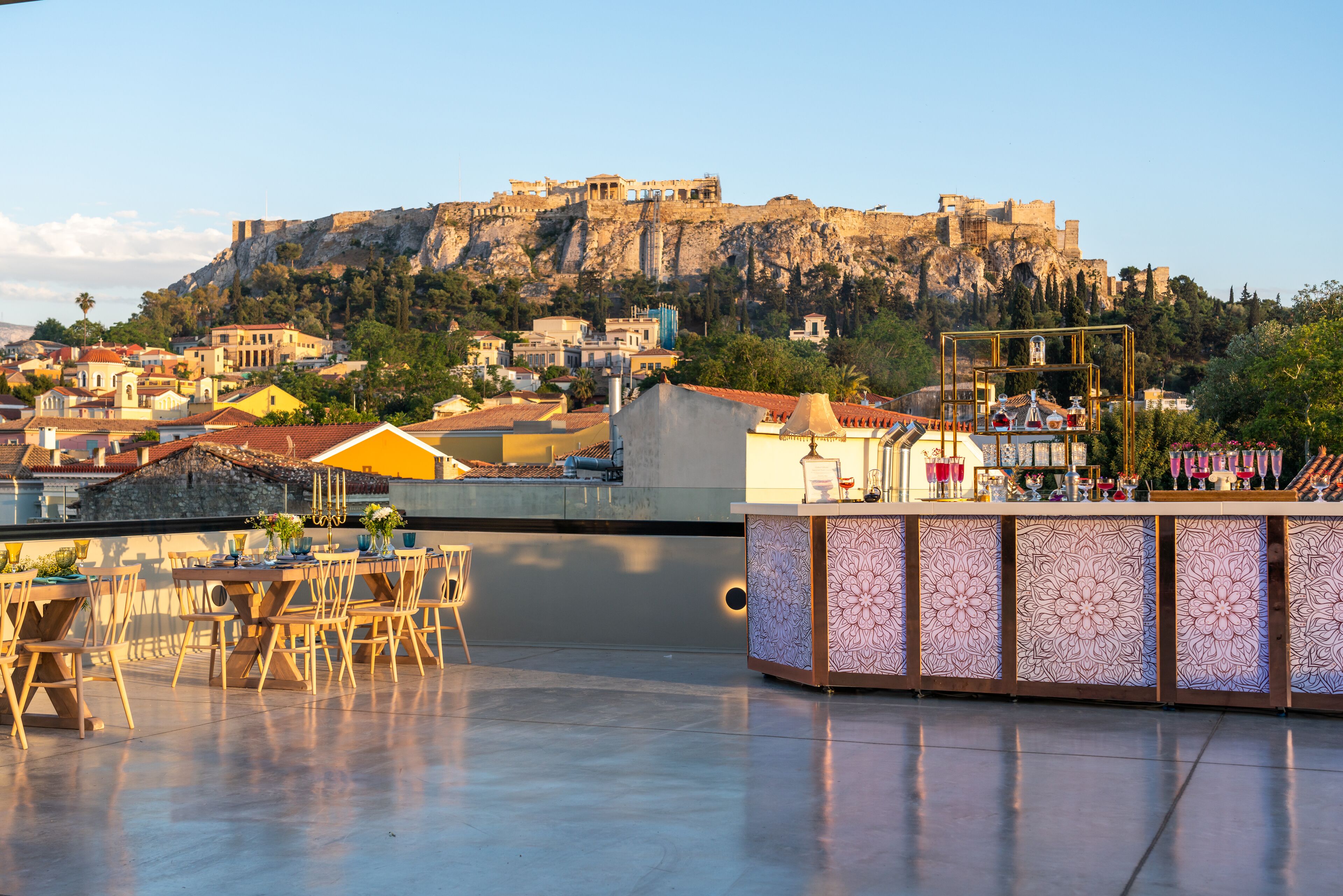 A rooftop terrace with a view of a historic castle, furnished tables, and a decorative bar area.