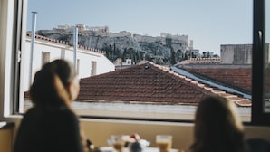 Une vue depuis une fenêtre donnant sur un paysage urbain, avec un bâtiment historique remarquable situé sur une colline.