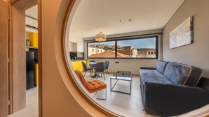 Un salon moderne comprenant un canapé, une table basse et un coin repas avec des chaises.