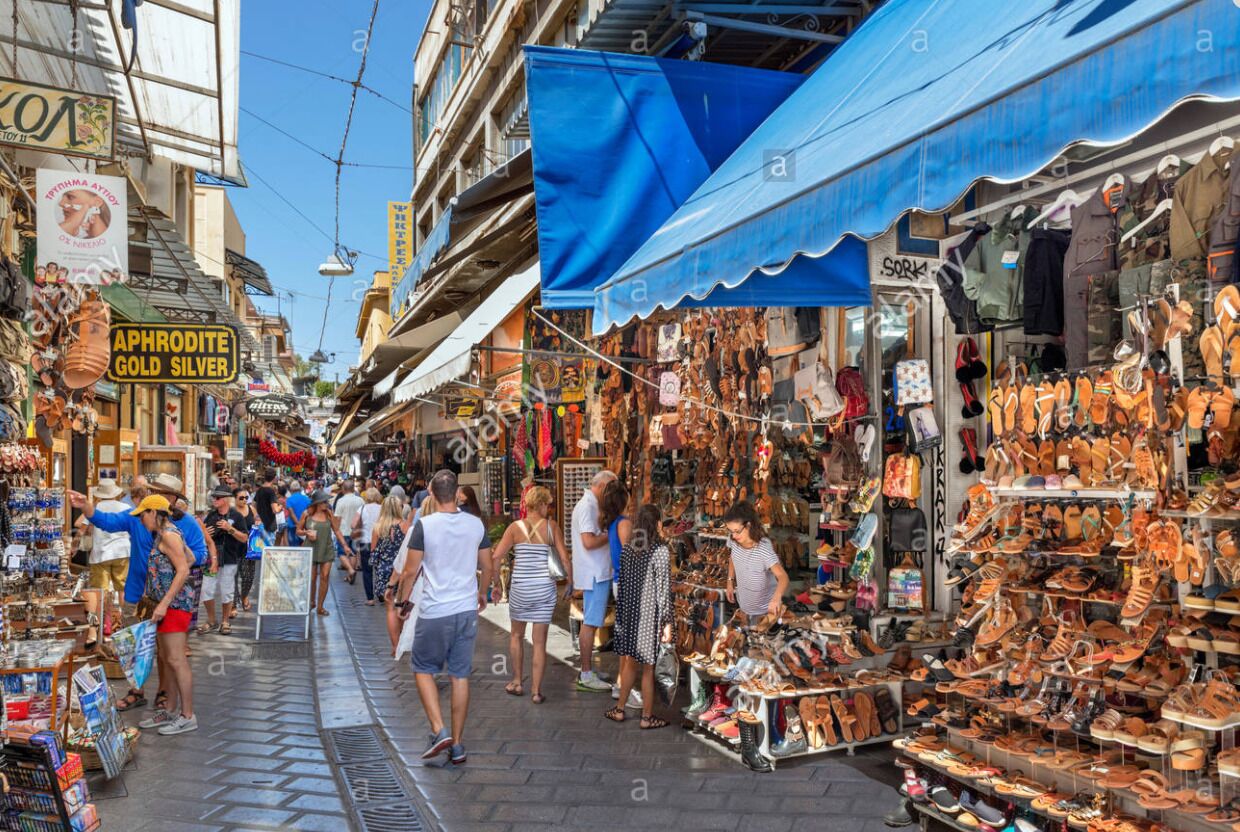 A bustling street market with various stalls selling shoes and accessories.