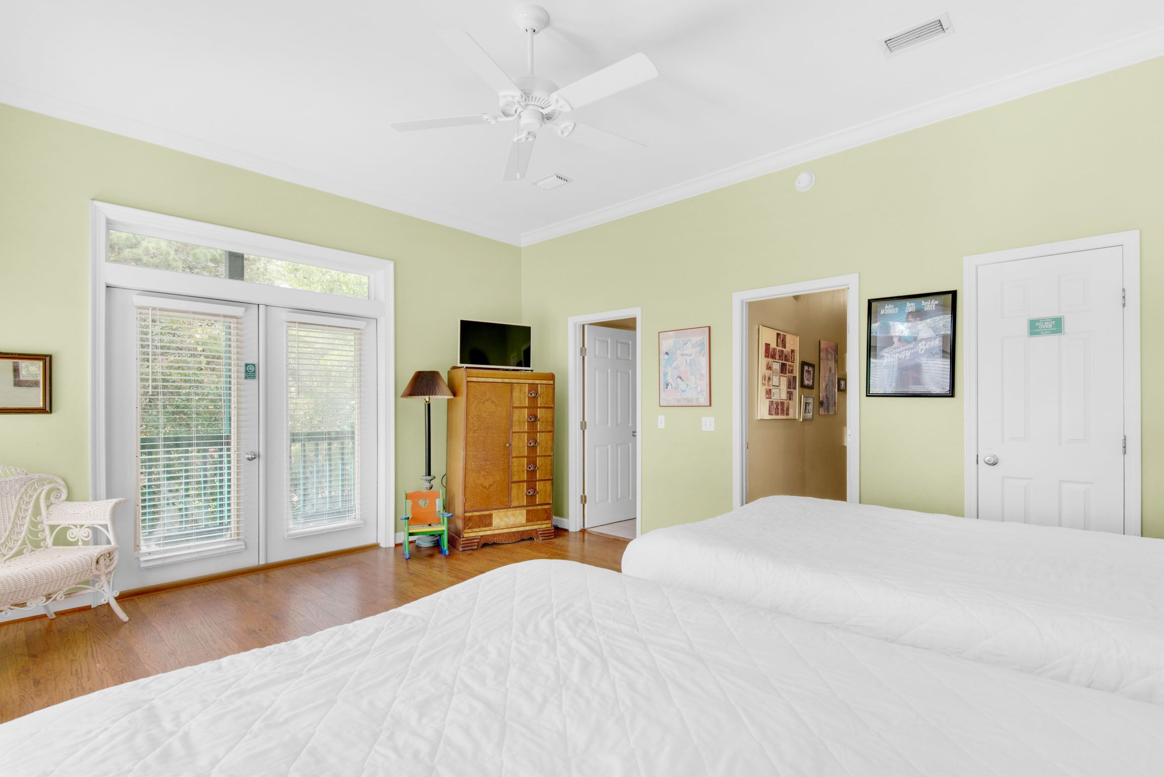 A bedroom with two beds, a ceiling fan, a wooden cabinet, and a television.